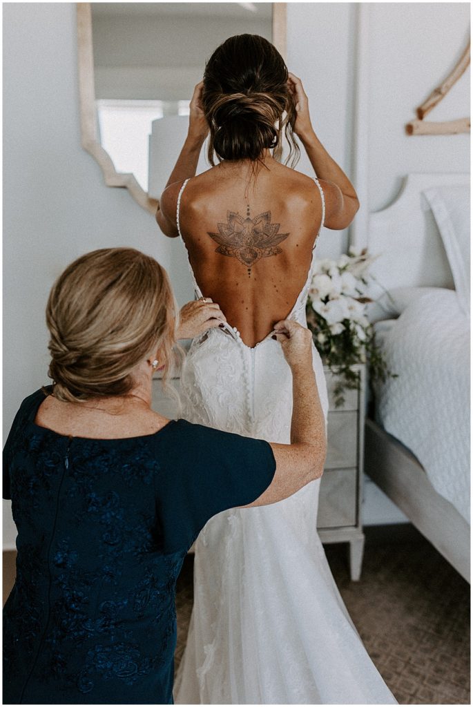 Mother of the bride is helping her get into her wedding dress