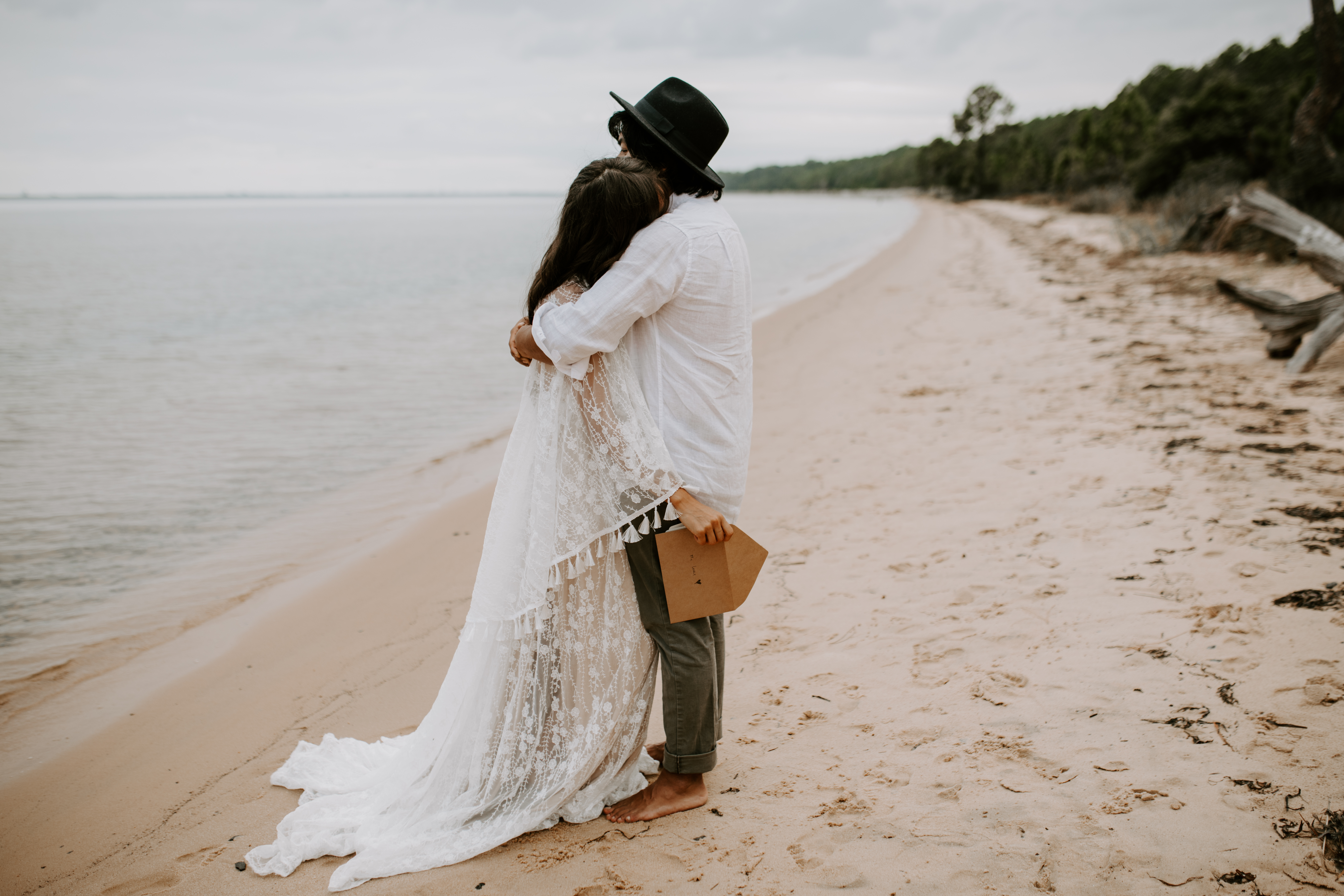 how to plan a destination wedding bride and groom hugging on the beach after saying private vows to each other