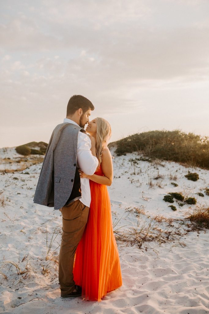 what to do after getting engaged man and woman cuddling on the sand dune