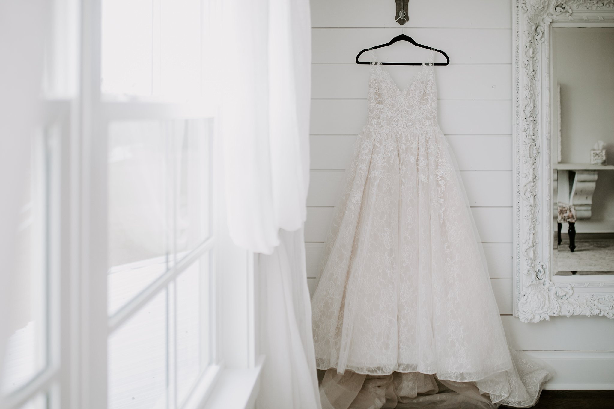 Rosie Creek Farms bridal room, wedding dress hanging against white shiplap on a black hanger