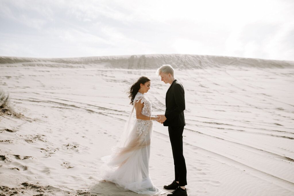 Eloping couple on sand dunes saying vows to each other