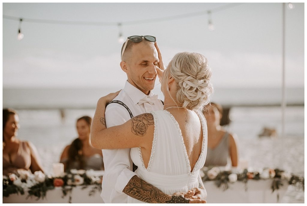 Bride is wiping away a tear on the groom's face during their first dance