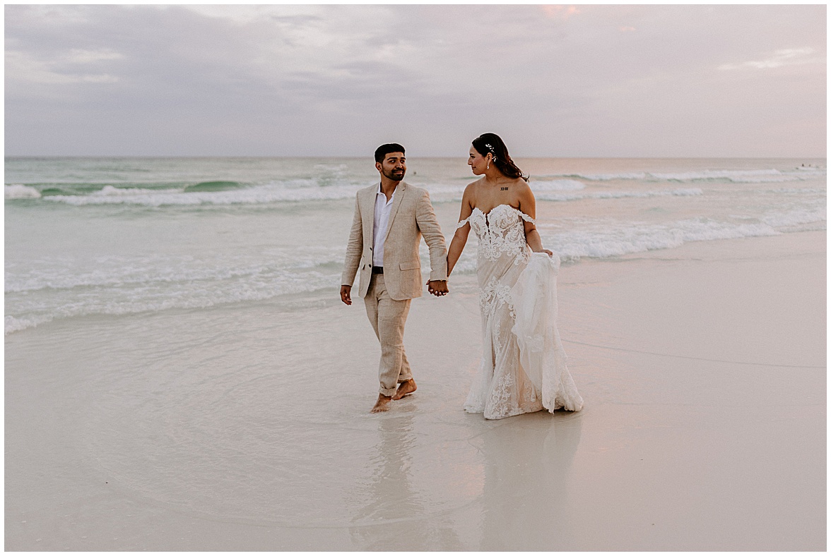 Bride and groom walking on the beach at sunset