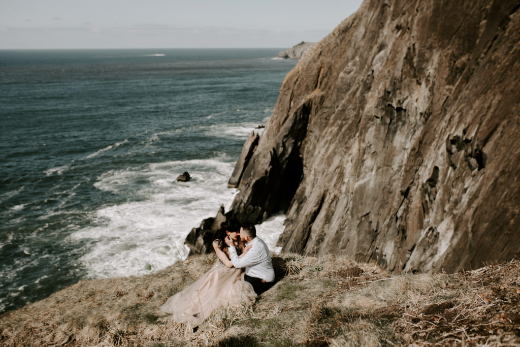 Couple sitting on the edge of a cliff on the Washington coast