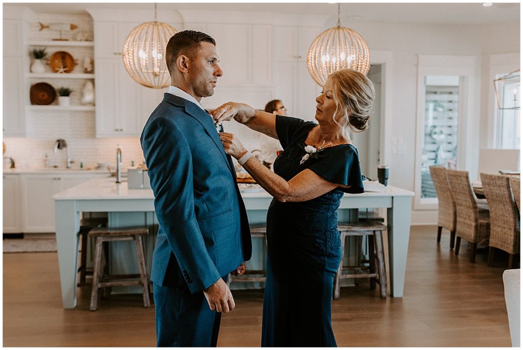 Mother of groom pinning flowers to the groom's tux