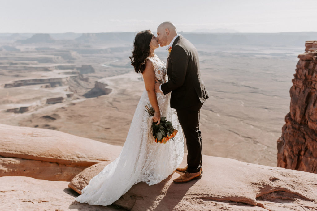 This couple planned a destination elopement, and they're standing on a canyon in Utah.