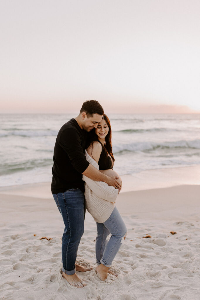 Couple cuddling on the beach during their destin maternity session