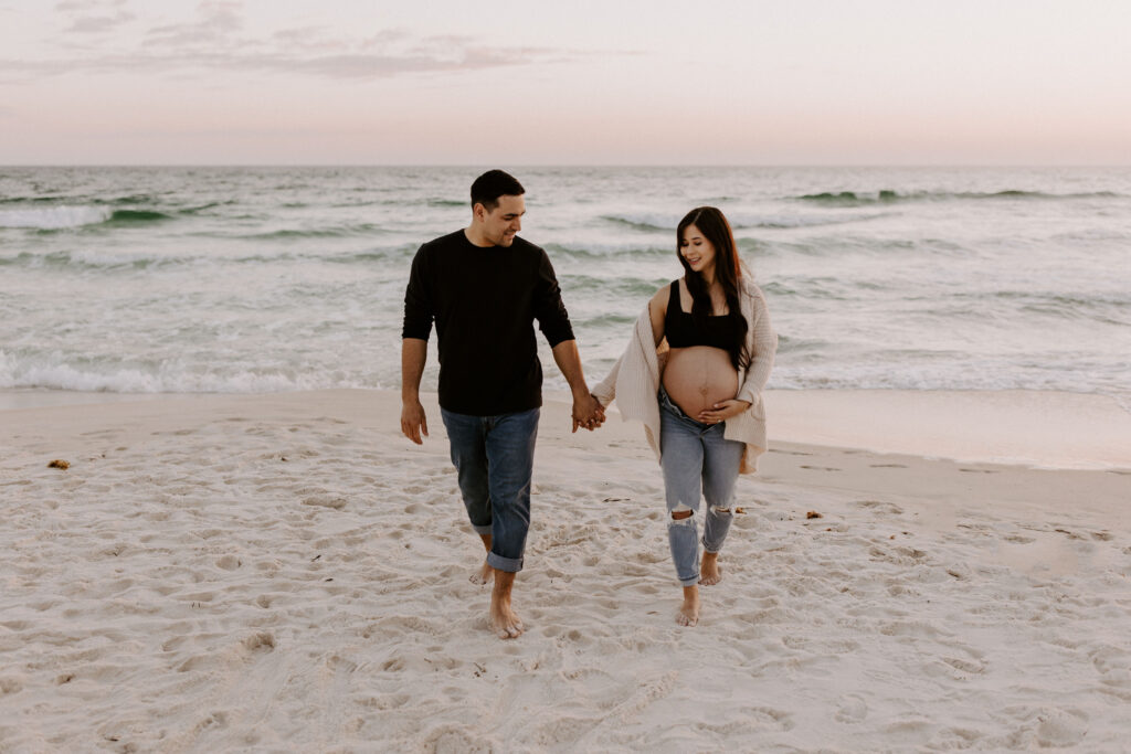 Couple walking on the beach during their destin maternity session