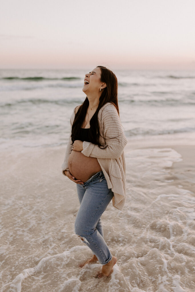 Portrait of a pregnant woman holding her belly and laughing