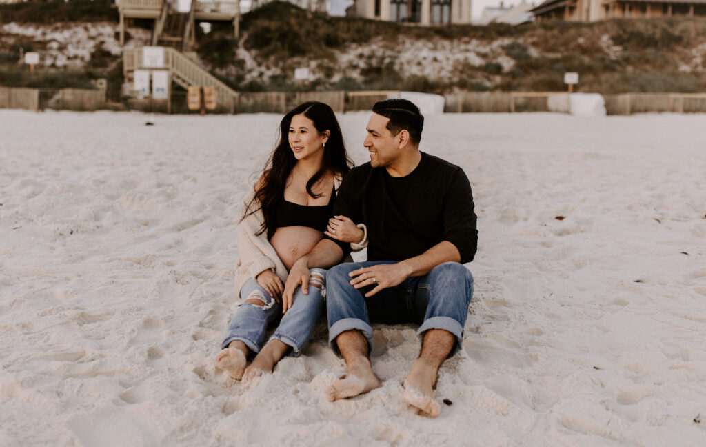 Couple sitting on the beach at their Destin maternity photography session