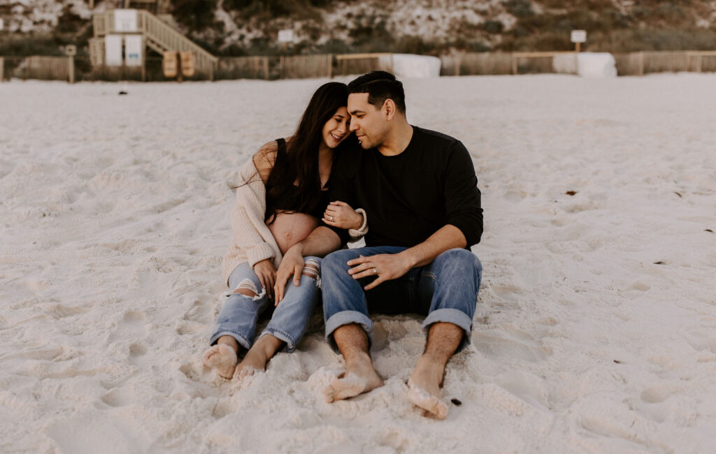 Couple sitting on the beach at their Destin maternity photography session