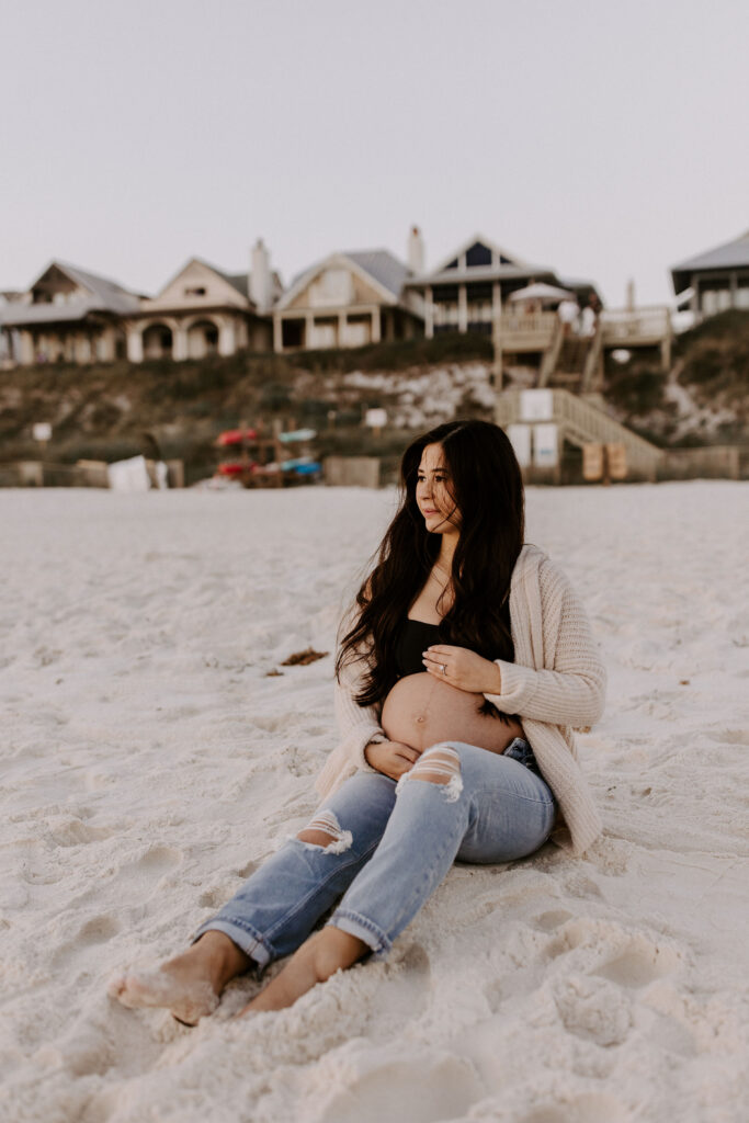 Woman sitting on the beach at her Destin maternity photography session