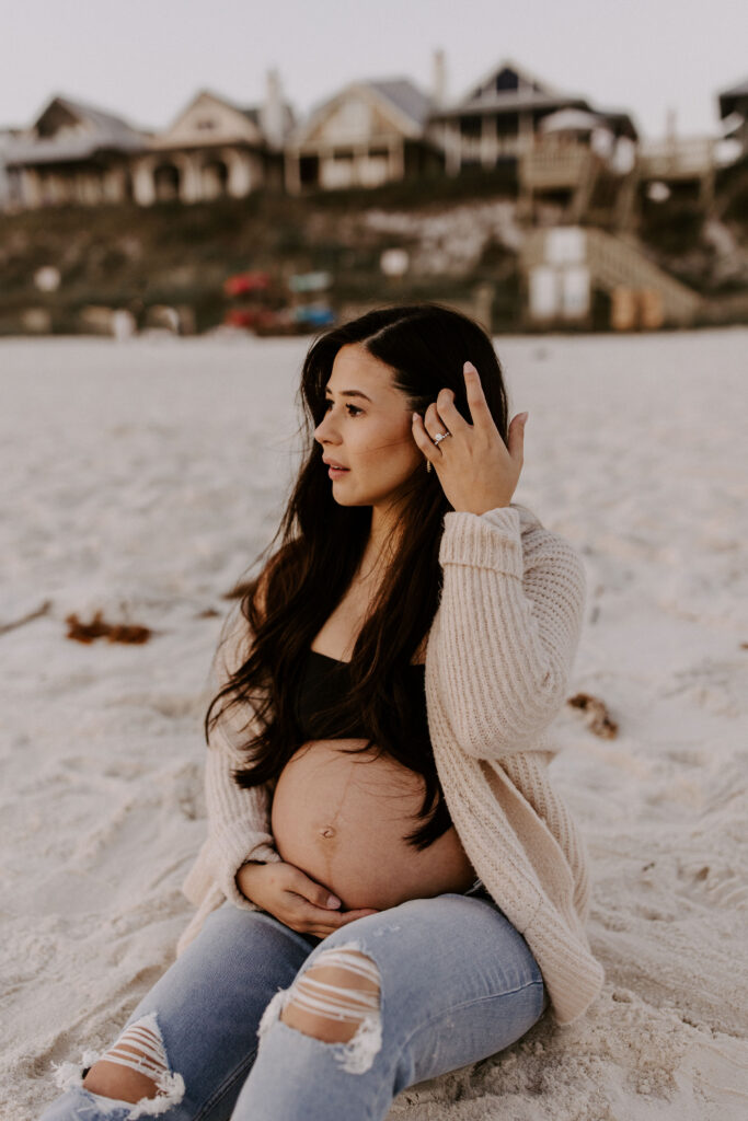 Woman sitting on the beach at her Destin maternity photography session