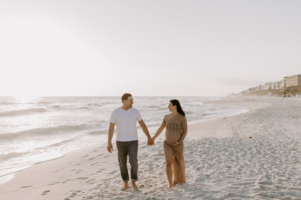 Couple walking on the beach during their Destin maternity photography session