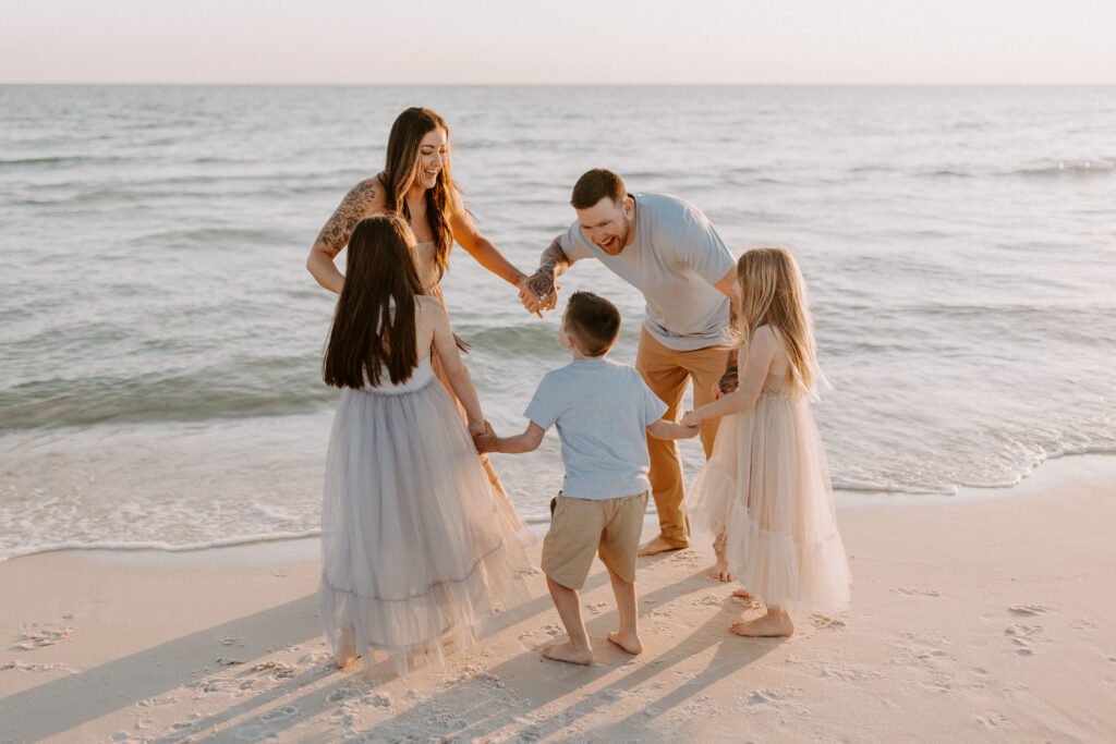 Family playing ring around the rosie on the beach